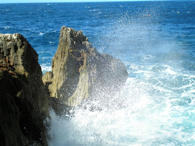 Lo spuntone di roccia che emerge dal mare viene continuamente lambito e riempito di schizzi di acqua marina.